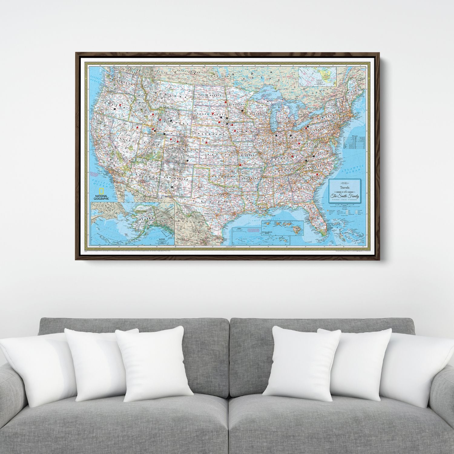 Framed Classic USA National Geographic travel pin map canvas hanging above gray sofa with white pillows