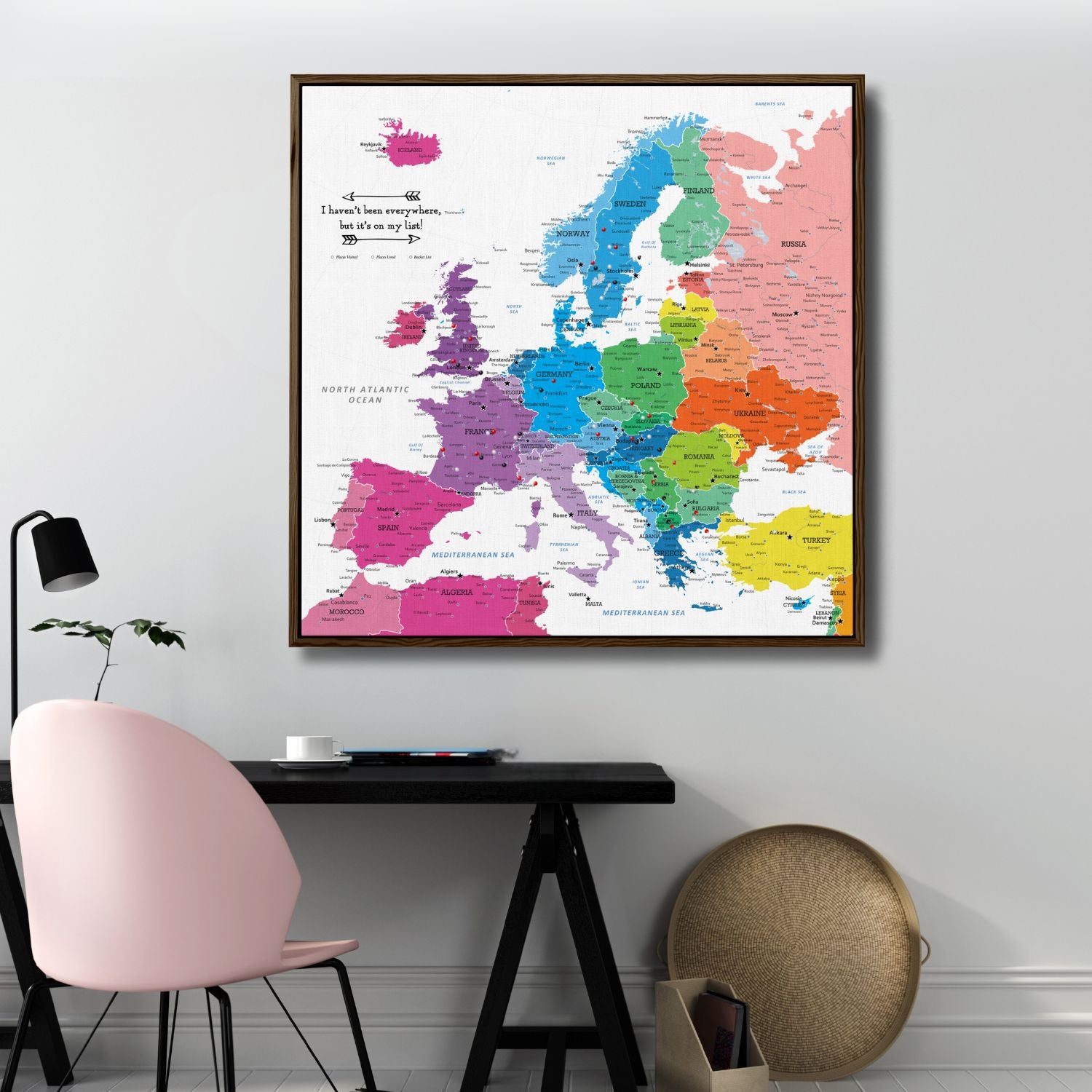 Colorful Europe travel map canvas with pins hanging above modern home office desk