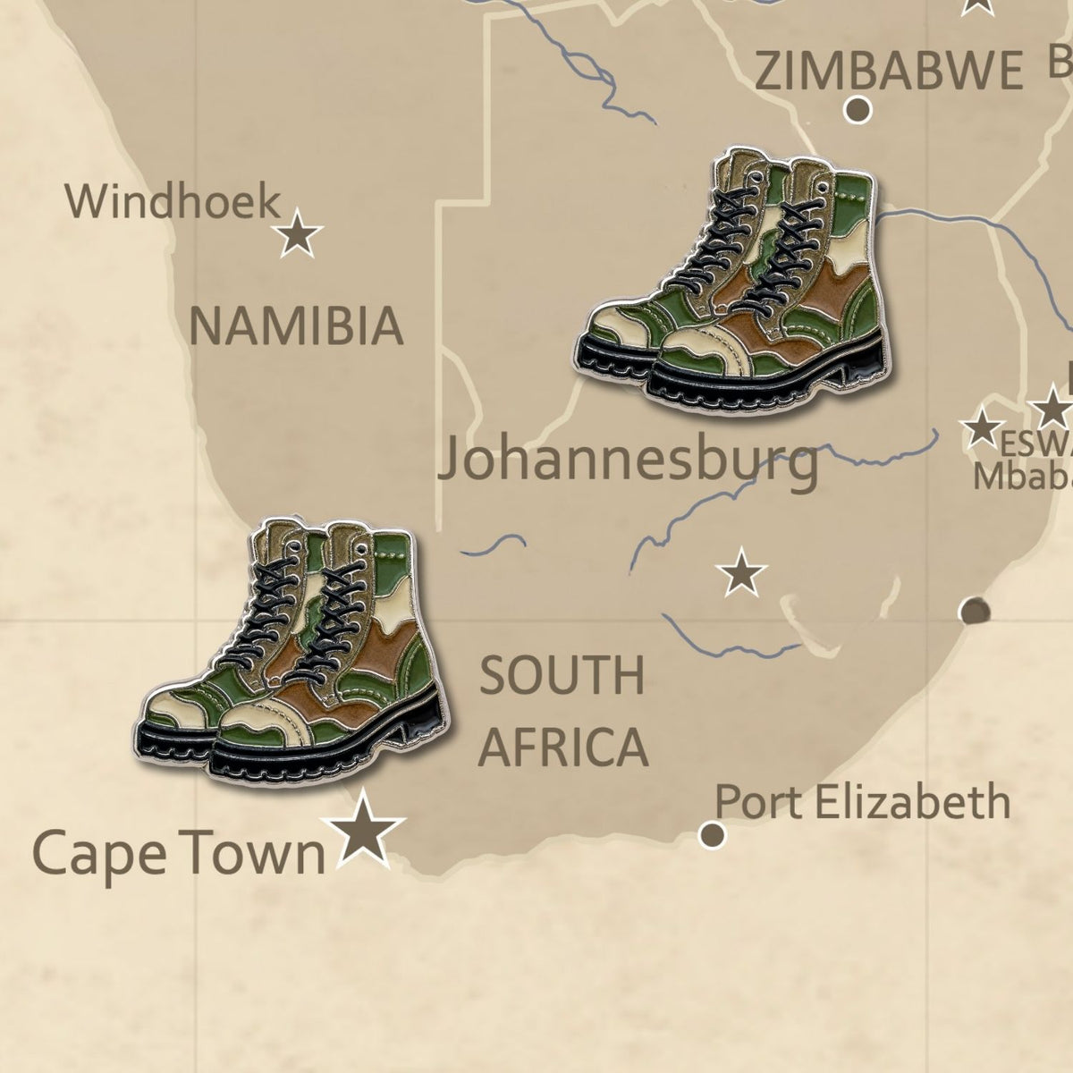 Two camo combat boot enamel map pins placed on South Africa vintage map display