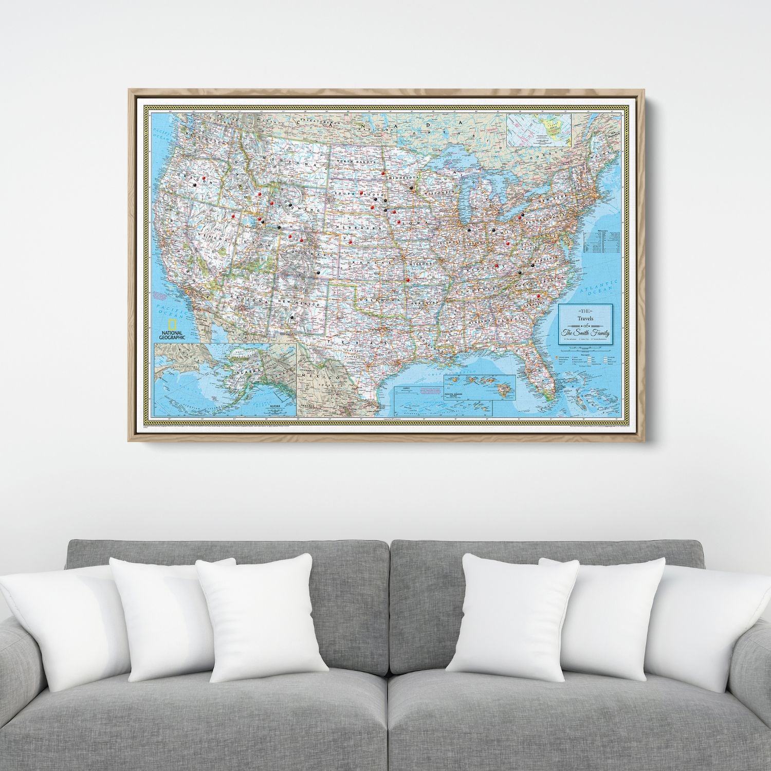 Framed National Geographic Classic USA travel pin map canvas hanging above gray sofa with white pillows