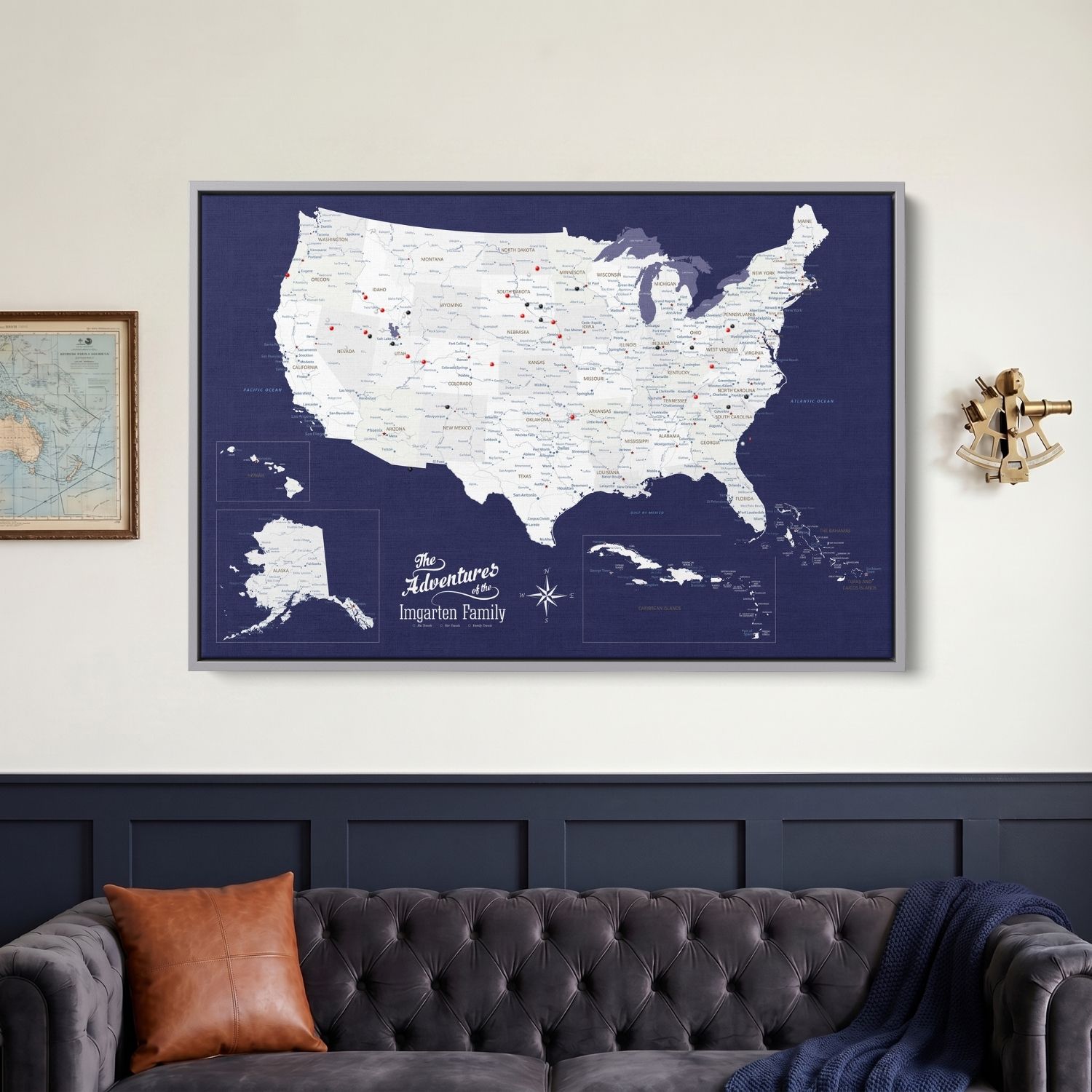 Framed navy canvas USA Caribbean travel map with red and black pins hung above tufted sofa