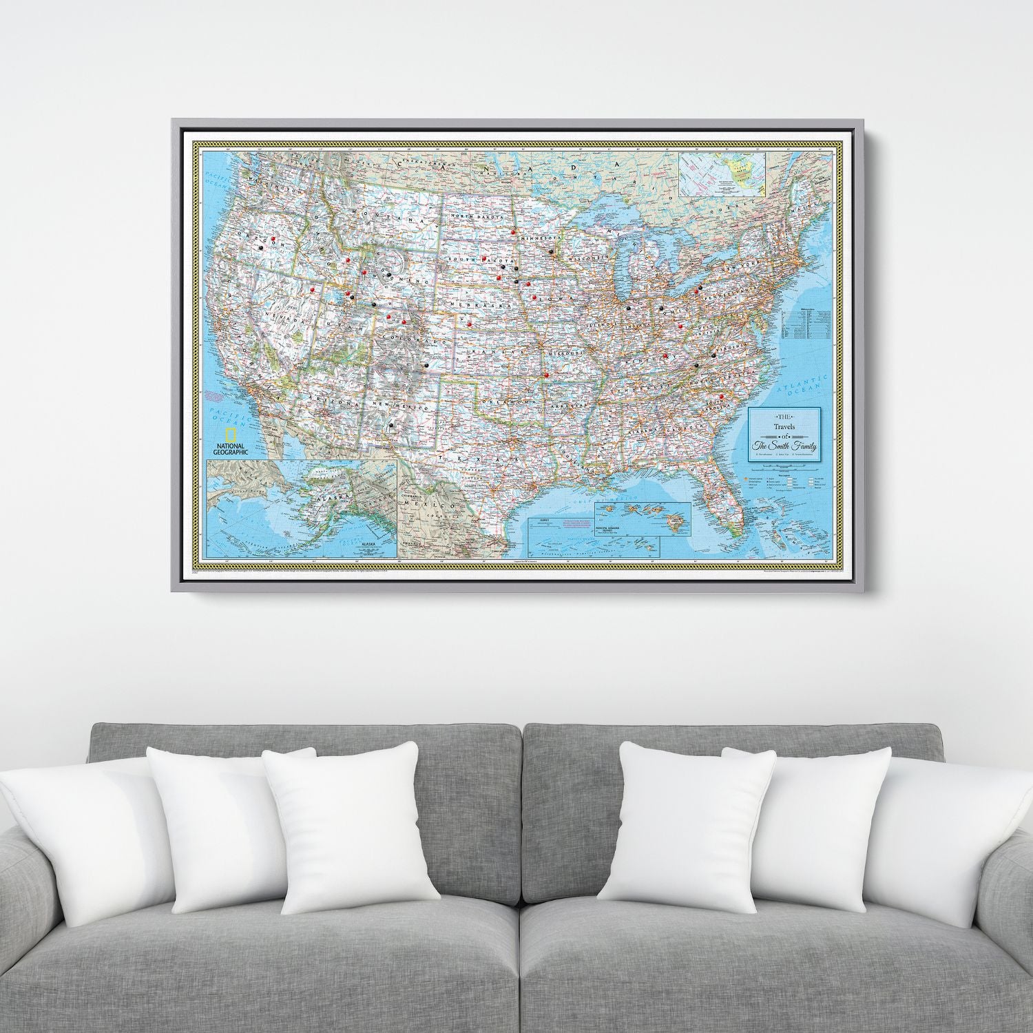 Framed National Geographic Classic USA travel pin map canvas hanging above gray sofa with white pillows