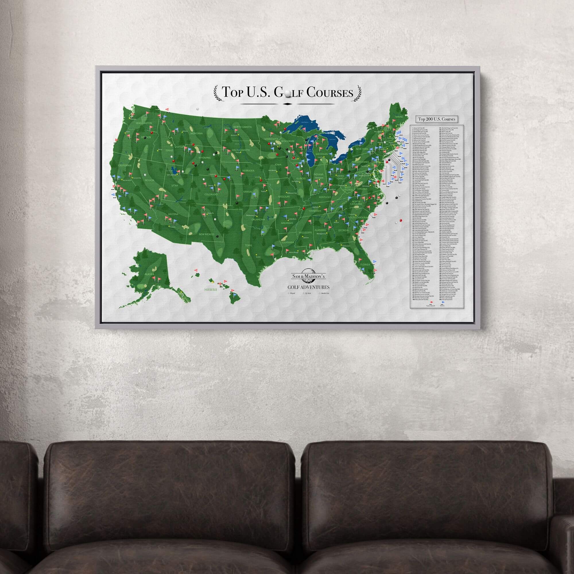 Framed Top US Golf Courses canvas travel map with pins displayed above dark leather sofa