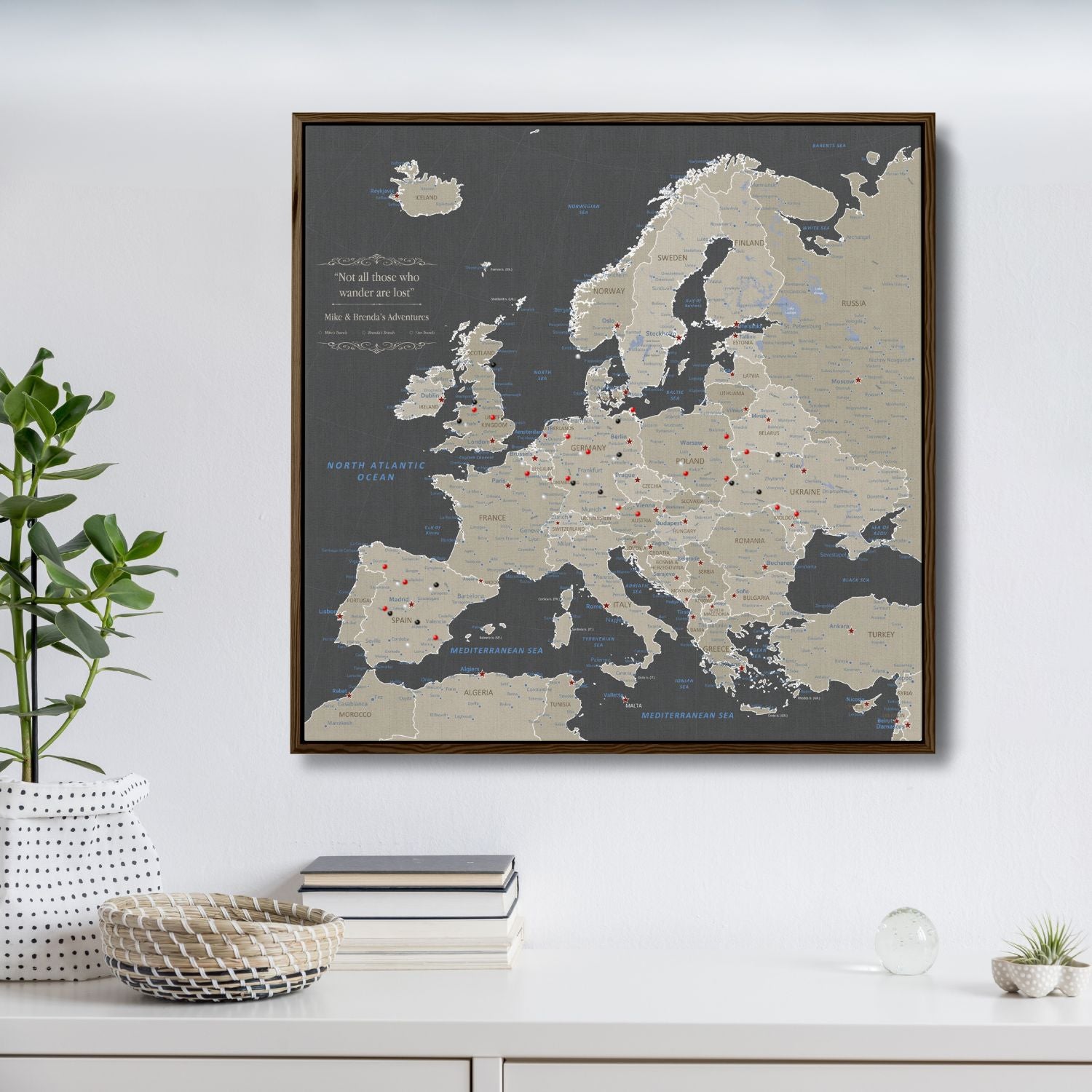 Earth toned Europe travel map canvas with red pins in dark walnut float frame on white wall