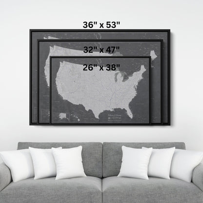 Three size options of Stormy Dreams USA canvas travel map with pins displayed above gray sofa