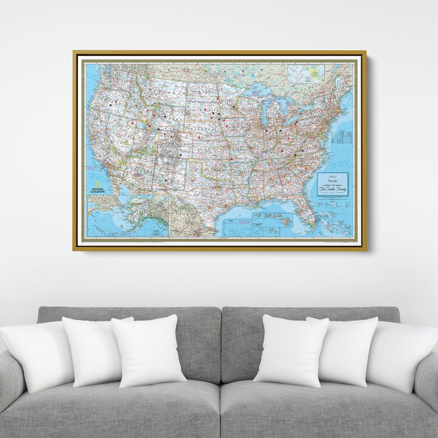 Personalized Classic USA National Geographic travel pin map in gold frame hanging above gray sofa