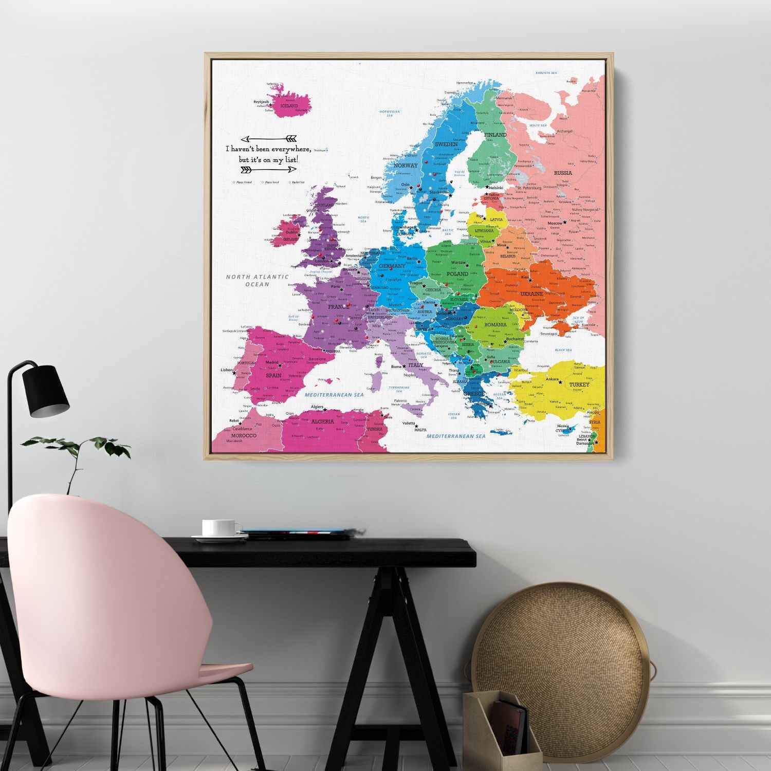Colorful Europe travel map canvas with wood frame hanging above modern desk workspace