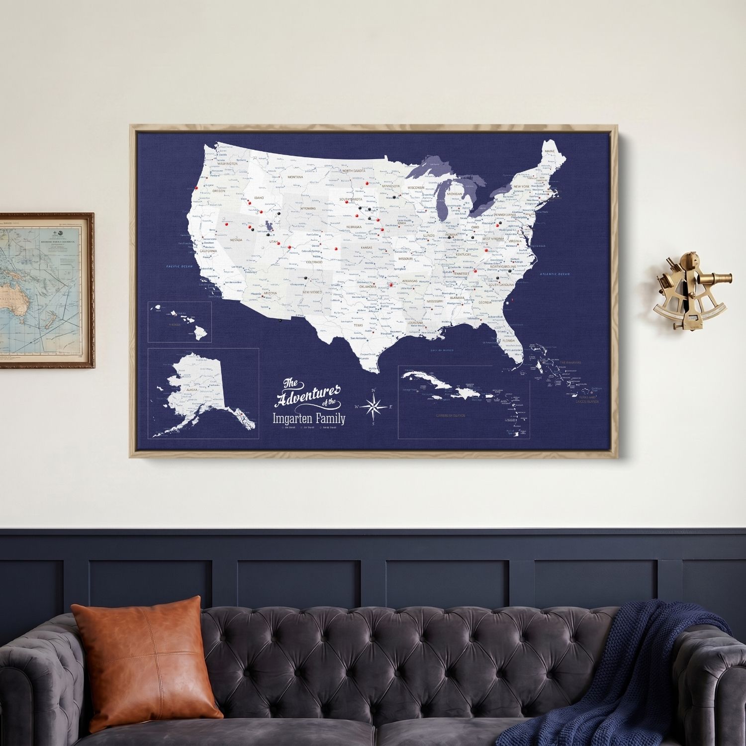 Personalized navy blue USA Caribbean canvas travel map with red pins hung above gray tufted sofa
