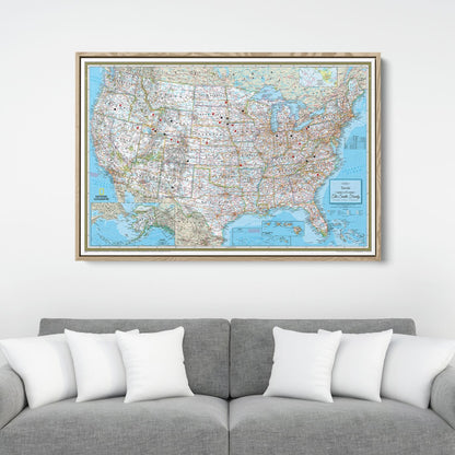 Framed National Geographic Classic USA travel pin map canvas hanging above gray sofa with white pillows
