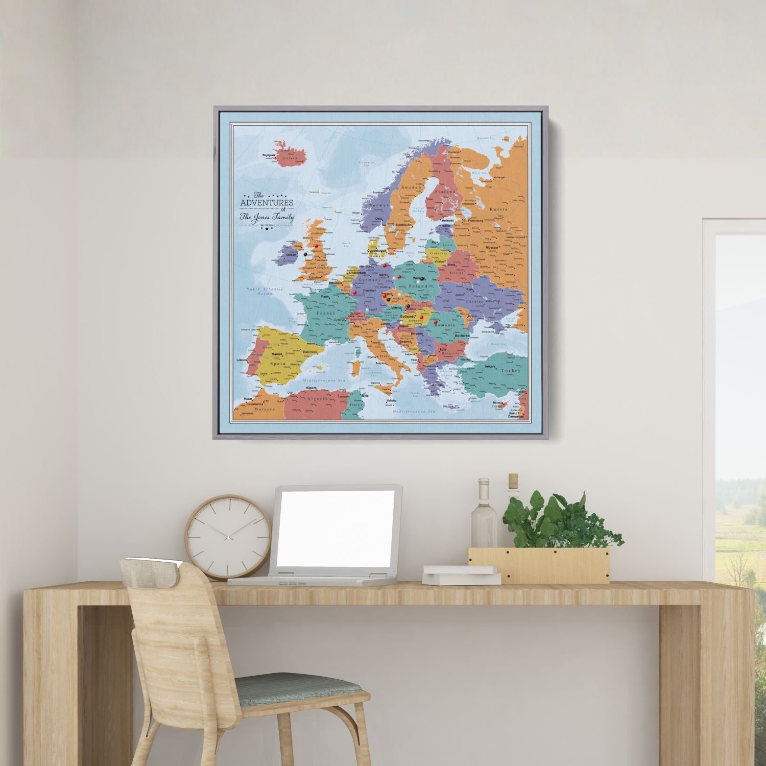 Framed blue oceans Europe travel map with push pins displayed above a modern wooden desk in home office setting