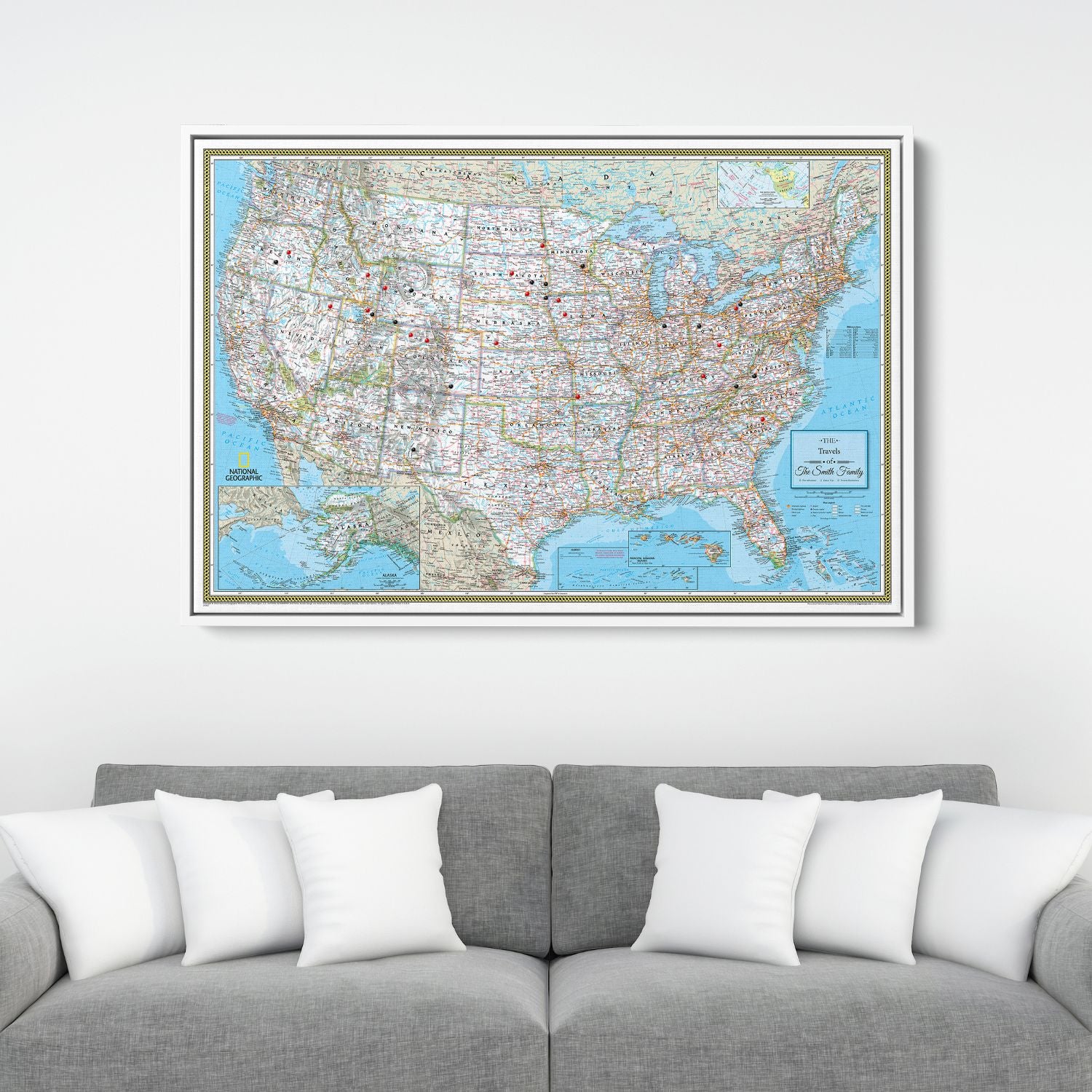 Framed National Geographic Classic USA travel pin map canvas hanging above gray sofa with white pillows